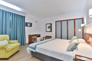 um quarto de hotel com uma cama e uma cadeira amarela em Hotel Arangues em Setúbal