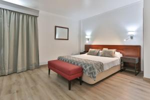 - une chambre avec un lit et un tabouret rouge dans l'établissement Hotel Arangues, à Setúbal