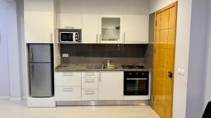 a kitchen with white cabinets and a sink and a refrigerator at T1 Família Luz in Mindelo