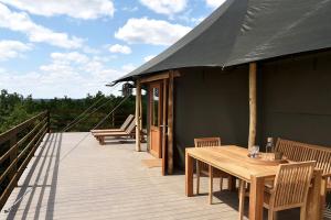a wooden deck with a table and chairs on it at Greenfields Glamping Durbuy in Durbuy