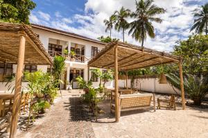 an outdoor patio with a table and a pergola at KIMA Serviced Beach House & Suites in Bwejuu
