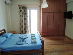 a bedroom with a bed with blue sheets and a window at Magic Ionian Apartments & Rooms in Himare