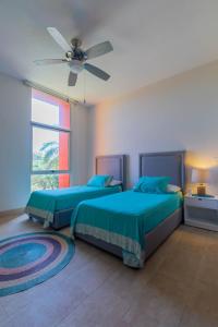 a bedroom with two beds and a ceiling fan at Isla Sunset Rentals at Sotavento in Isla Mujeres
