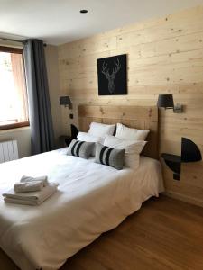 una camera da letto con un grande letto bianco e pareti in legno di Chalet Hibou a Les Deux Alpes