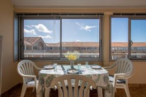 a dining room with a table and chairs and windows at Emplacement idéal - Trou du Diable sur la Corniche in Les Bussolleries