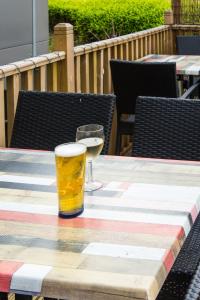a glass of beer and a glass of wine on a table at ibis Styles Haydock in Haydock