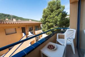 a balcony with two white chairs and a table at Apartamentos Marblau in Tamariu