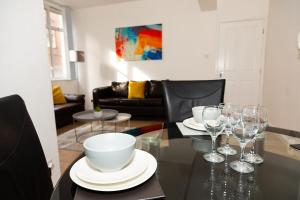uma sala de jantar com uma mesa com pratos e copos de vinho em Alexander Apartments Powdene House em Newcastle upon Tyne