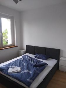 a bedroom with a bed with blue sheets and a window at Marshal Foch Apartment in Grudziądz