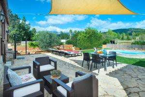 un patio con mesa, sillas y piscina en Owl Booking Villa Garreta - Rustic Stay with Mountain Views, en Campanet