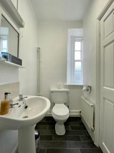 Baño blanco con aseo y lavamanos en Harts Head Hotel en Settle