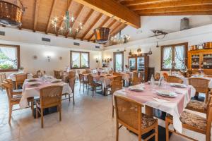 comedor con mesas y sillas y techos de madera en Cadria Nature & Bike Hotel, en Lenzumo di Concei