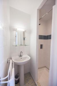 een witte badkamer met een wastafel en een douche bij Hôtel de la Place in Mézel