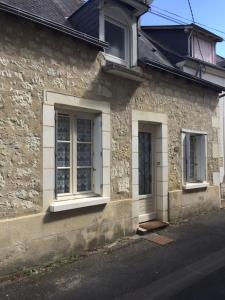 een stenen huis met twee ramen en een deur bij Le coin des Halles dans le vignoble de Bourgueil in Bourgueil