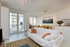 a living room with a white couch and some windows at Modern appartement met doorkijk op de duinen in Cadzand