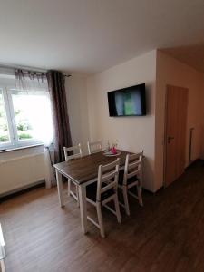 a dining room table with chairs and a television on the wall at Landgasthof Fischer in Lichtenfels