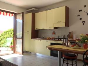 een keuken met witte kasten en een houten tafel bij Irina’s house with view on like and swimming pool in Riva di Solto