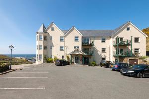 a large building with cars parked in a parking lot at Beachcombers Apartments in Newquay