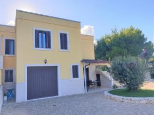 una gran casa amarilla con garaje en Villa Arisa with pool, en Selva di Fasano