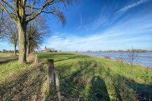 un campo con una valla y un árbol y agua en Fischerdorf-Fewo, en Kalkar