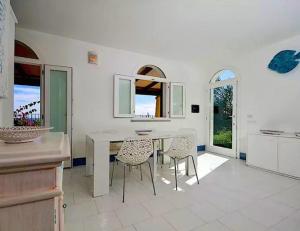a white kitchen with a table and chairs in it at Magnificent Villa: SUPER PANORAMIC in Costa Rei