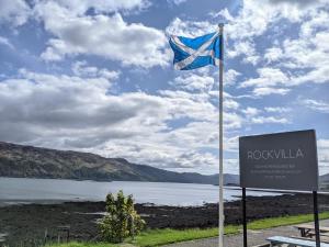 a flag on a pole next to a lake at Rockvilla Guest House in Lochcarron