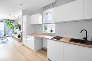 ミエルノにあるApartament AP10の白いキャビネットと木製のカウンタートップを備えたキッチン