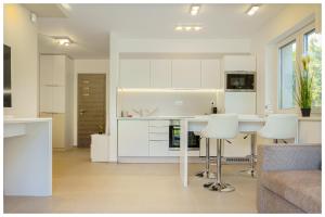 uma cozinha com armários brancos e uma mesa e cadeiras em Kenese Regatta Apartman em Balatonkenese