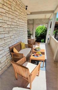 a patio with chairs and tables and a stone wall at B&K in Tisno