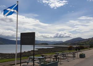 a flag and picnic tables next to a lake at Rockvilla Guest House in Lochcarron