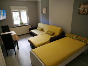 a living room with a couch and a yellow bed at Fehérló Vendégház & Restaurant in Bük