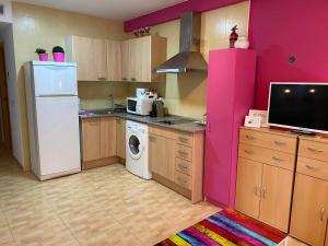 eine Küche mit einem weißen Kühlschrank und einer rosa Wand in der Unterkunft Apartamentos Alcañiz, Ana in Alcañiz