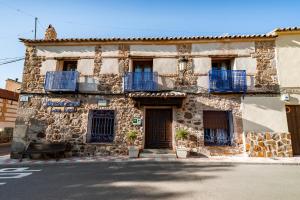 an old stone building with blue balconies on a street at Casa Rural Álamo Grande in Layos