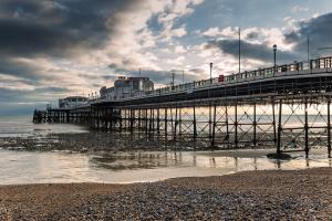 um cais na praia com um céu nublado em The Burlington em Worthing