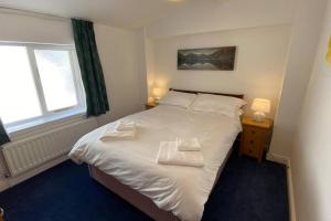 1 dormitorio con 1 cama blanca y 2 almohadas en Poet's Corner - flat close to centre of Keswick en Keswick