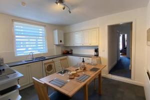 una cocina con mesa de madera y sillas. en Poet's Corner - flat close to centre of Keswick en Keswick