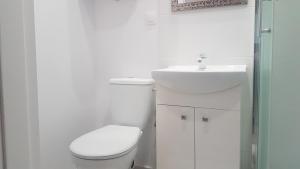a white bathroom with a toilet and a sink at Domki u Remika in Pobierowo