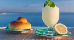 a drink in a glass next to a sandwich and a slice of lemon at Duomo Square Apartment in Taormina