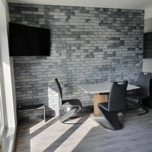 Una mesa y sillas en una habitación con una pared de ladrillos. en Berylowa Apartament, en Konin
