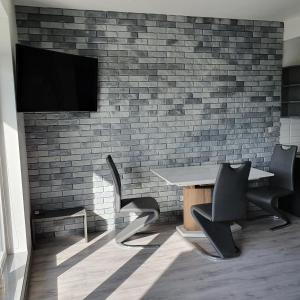 una camera con tavolo, sedie e TV su un muro di mattoni di Berylowa Apartament a Konin