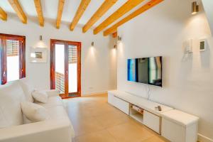 een woonkamer met een witte bank en een tv bij Duplex Palma Apartment - with garage in Palma de Mallorca