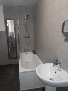 een badkamer met een bad, een wastafel en een douche bij The Vaults in Wrexham