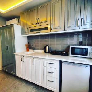 a kitchen with white cabinets and a microwave at Ararat Apart in Istanbul