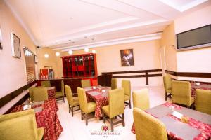 a restaurant with tables and chairs and a tv at Royalton Hotels Abuja in Abuja