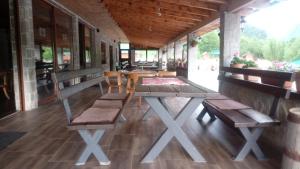 a porch with a picnic table and benches on it at Cottage Rafting Kljajevića Luka in Pljevlja