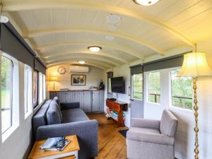 ein Wohnzimmer in einem winzigen Haus mit einer Decke in der Unterkunft The Carriage at High Barn Heritage in Halstead