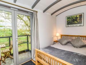 ein Schlafzimmer mit einem Bett und einer Glasschiebetür in der Unterkunft The Carriage at High Barn Heritage in Halstead