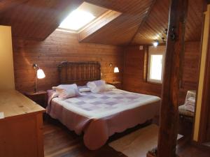 ein Schlafzimmer mit einem Bett in einer Holzhütte in der Unterkunft Casa dos Muros turismo rural y actividades en la Ribeira Sacra in Pantón