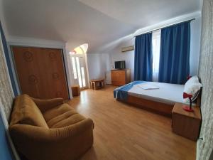 a bedroom with a bed and a couch and blue curtains at Villa ANelu in Mamaia Sat/Năvodari