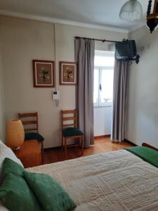 1 Schlafzimmer mit einem Bett, 2 Stühlen und einem Fenster in der Unterkunft Casa Araci in Vieira do Minho